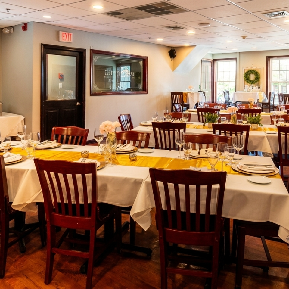 A restaurant dining room with multiple tables set with white tablecloths, yellow runners, and place settings.